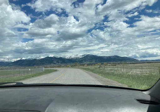 snow capped mountains and big sky seen through car windshield