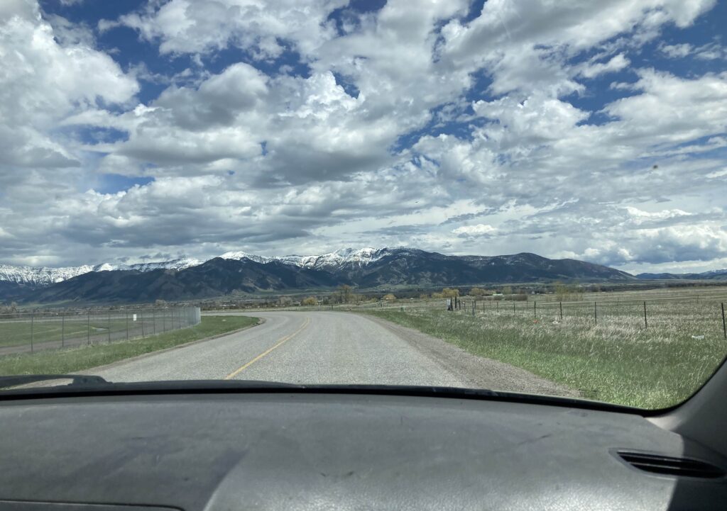 snowy mountains and big sky seen through car windshield