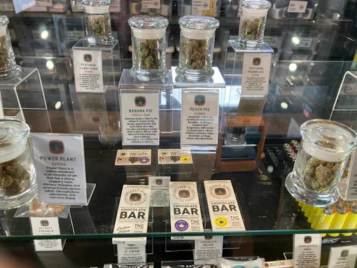 jars of weed and branded chocolate bars on glass shelf