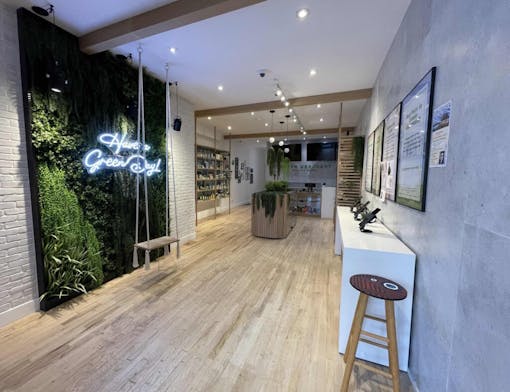 interior shot including wall made of plants with a neon sign overlaid on it