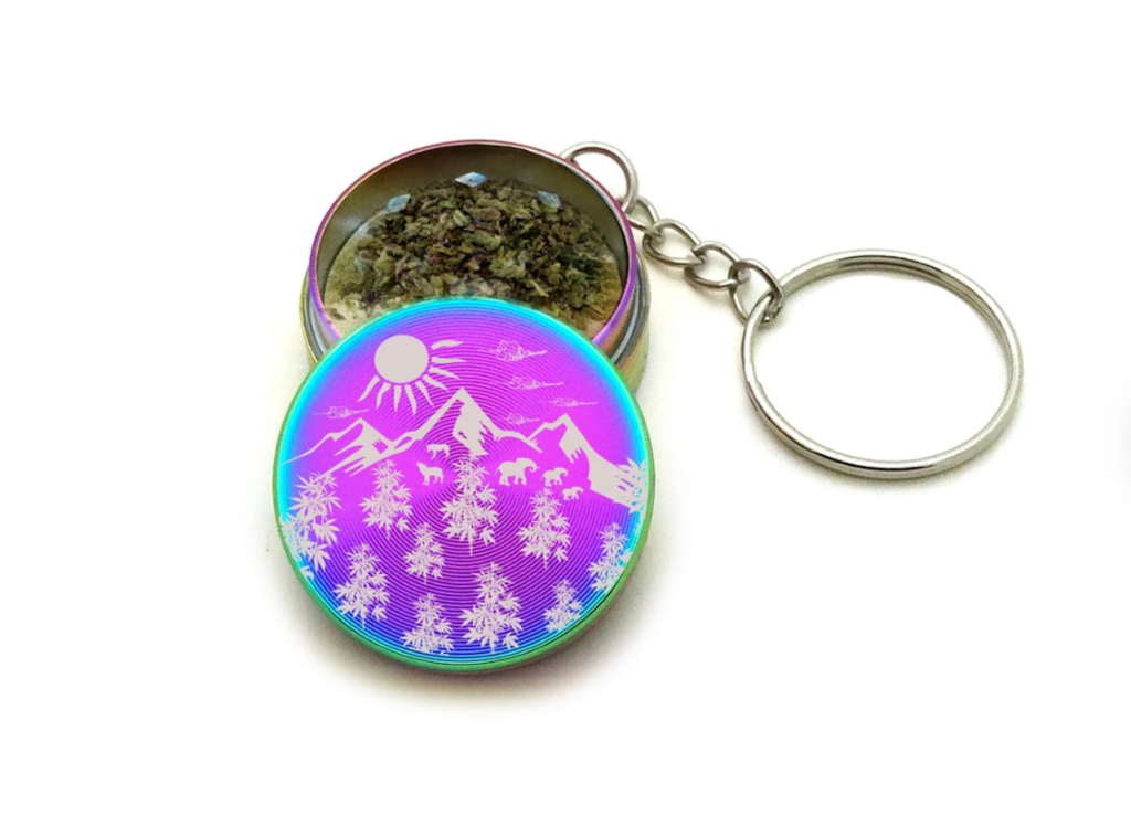 Photo of a mini grinder keychain engraved with a mountain landscape.