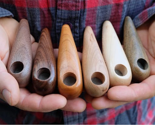 hands holding multiple wooden pipes in different shades