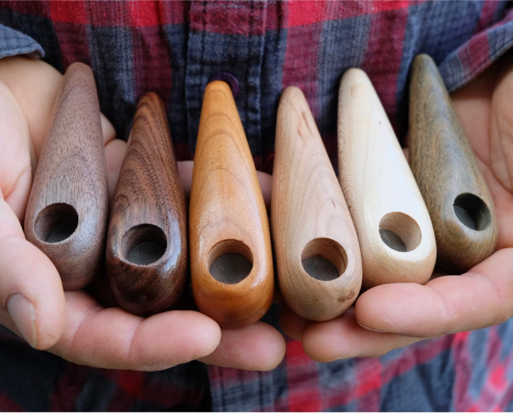 Hands hold several wooden pipes of different shades