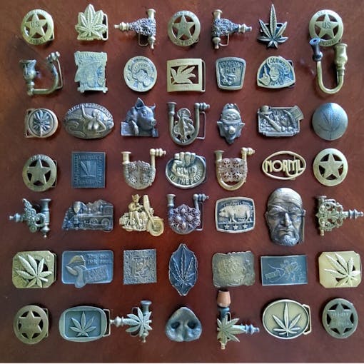 large collection of cannabis belt buckles, some that function as pipes