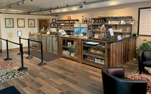 shop interior, with wooden floors, long wooden sales counter and leather chairs in corner