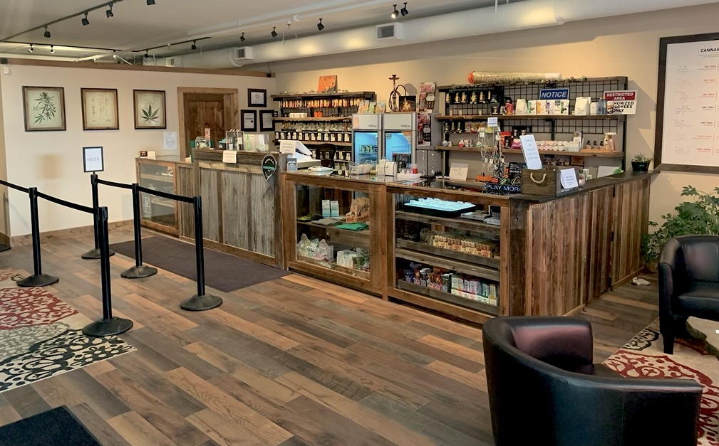 Shop fittings with a wooden floor, a long wooden sales counter and leather armchairs in the corner