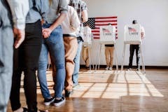 line of people stand in line to vote at indoor polling location