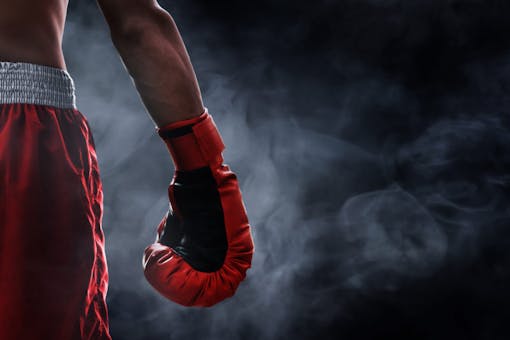 Boxer holds glove standing smoke.