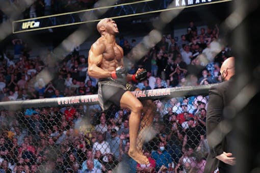 Kamaru Usman celebrates his win atop the octagon fence after a UFC 261 mixed martial arts bout against Jorge Masvidal early Sunday, April 25, 2021, in Jacksonville, Fla. (Gary McCullough, The Associated Press)
