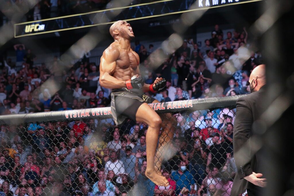 Kamaru Usman celebrates his victory on the octagon fence after a UFC 261 mixed martial arts fight against Jorge Masvidal early Sunday, April 25, 2021 in Jacksonville, Fla. (Gary McCullough, The Associated Press)