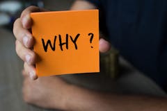 Hand holding an orange Paper with the word why - Why?, Business Concept