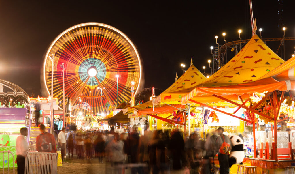 A fairground in the center is fully lit at night, with movement evident in this long exposure at the state fair