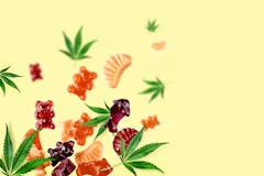 Chewing candies, marmalade with CBD oil and THC. Colored marmalades fly along with cannabis leaves. Colorful creative background, minimalism.
