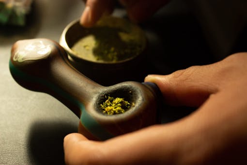 Person packing a bowl with weed from a grinder