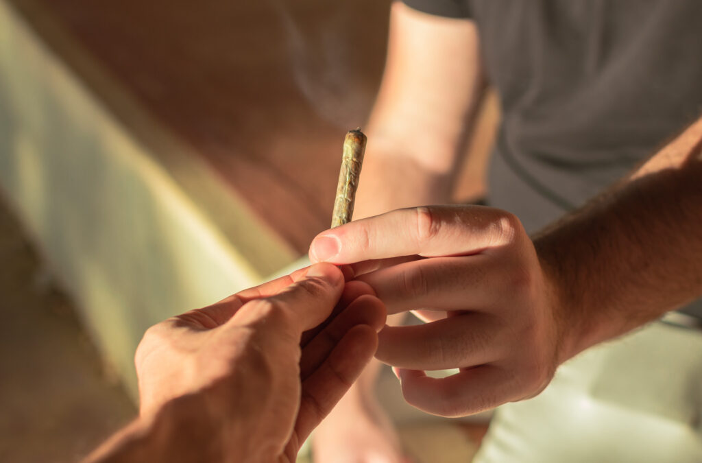 Young people share a marijuana joint during a sunset on the street.