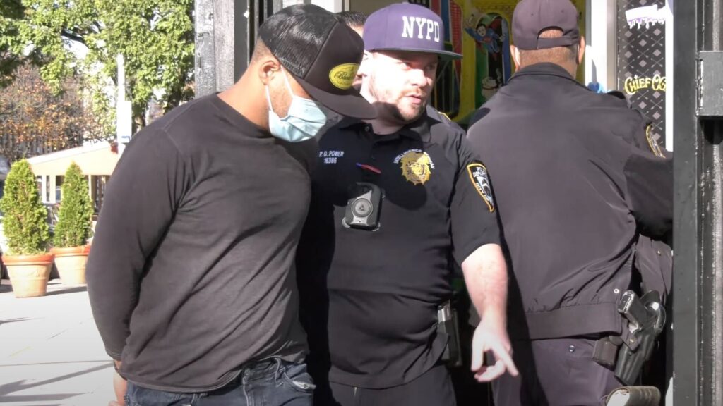 An NYPD officer leads a man bound into police custody from the Big Chief smoking facility in Brooklyn. Authorities have not released the names of the two people arrested in Thursday's raid. (LNN New York)