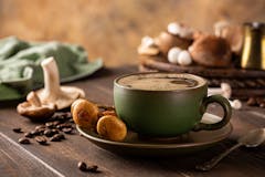 Mushroom coffee in green cup on wooden background. New Superfood trendy healthy concept with copy space, selective focus.
