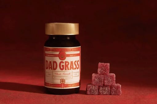 jar of gummies with small pyramid of red gummies next to it against dark red background