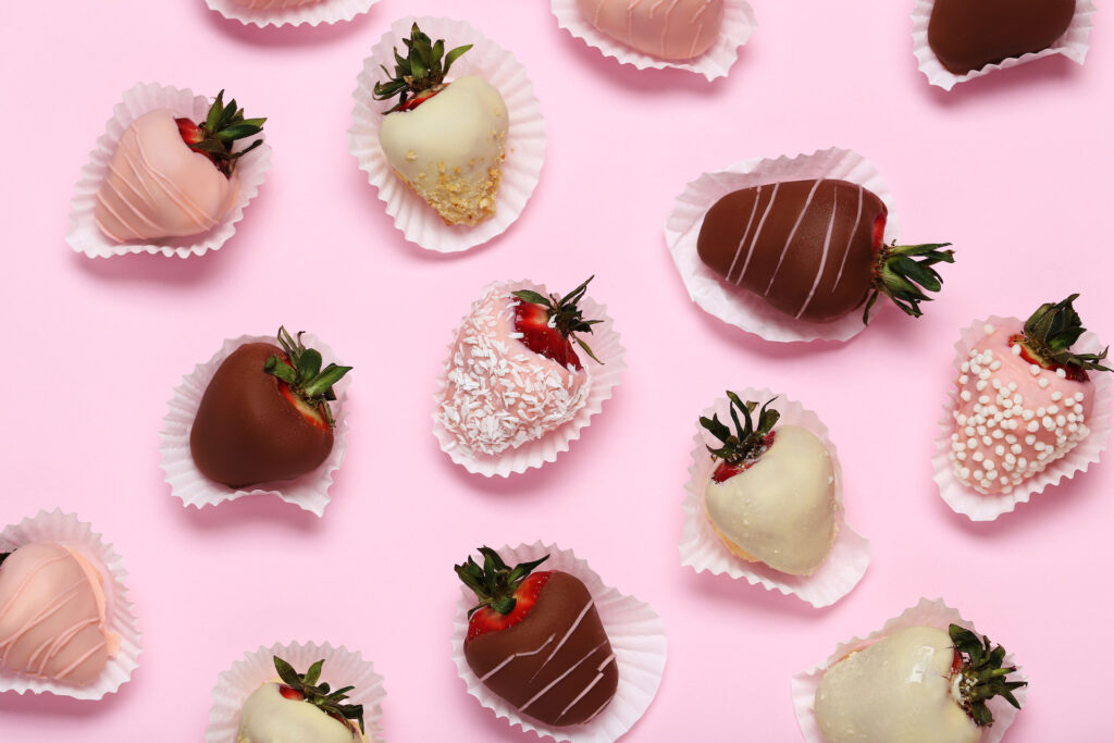 Strawberries covered in chocolate, white chocolate, on a pink background