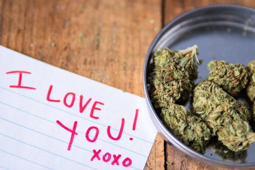 Medical marijuana flower with words "I Love You!" written on paper in red ink.