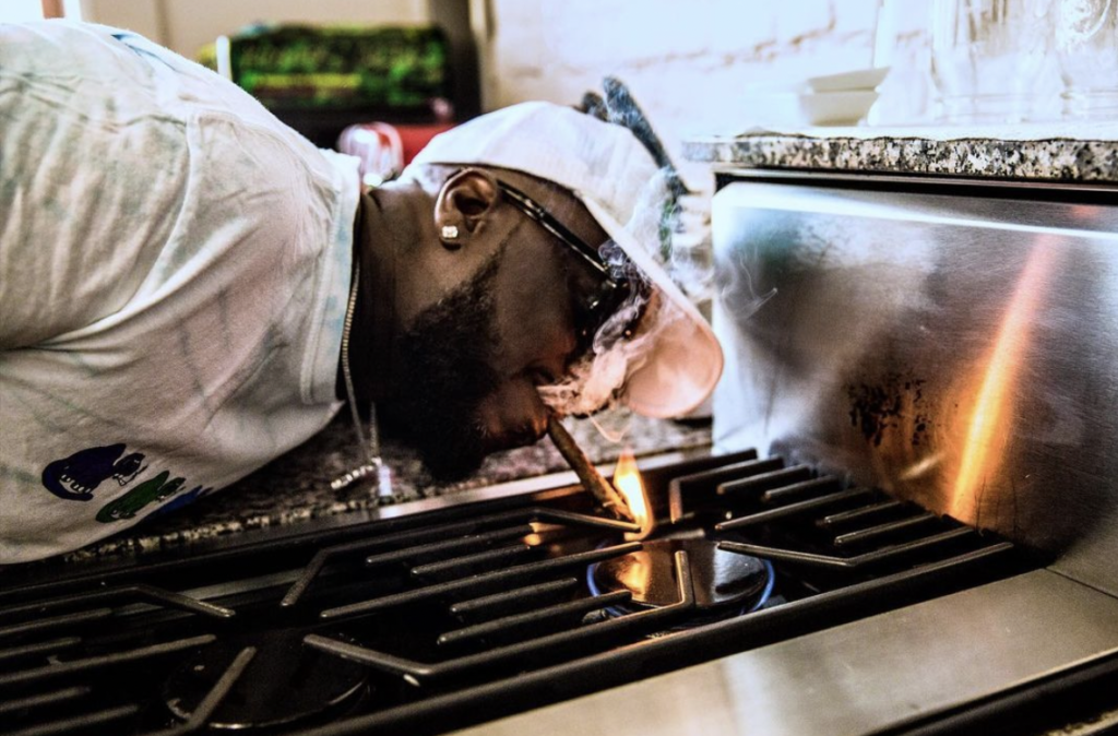 Shiest Bubz lights a blunt on a stovetop flame. (Instagram / @adonisisbored)