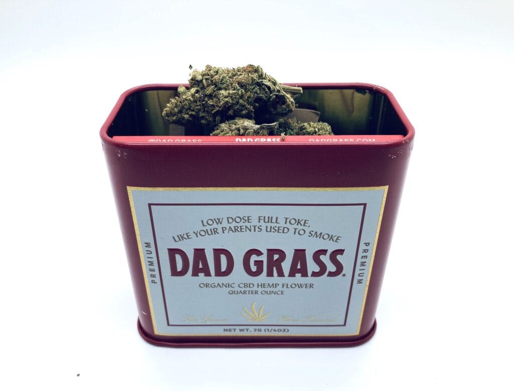 Red tin of open CBD flowers with buds on top