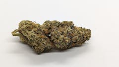 A big dense cannabis nug in green and purple tones with thick trichomes.