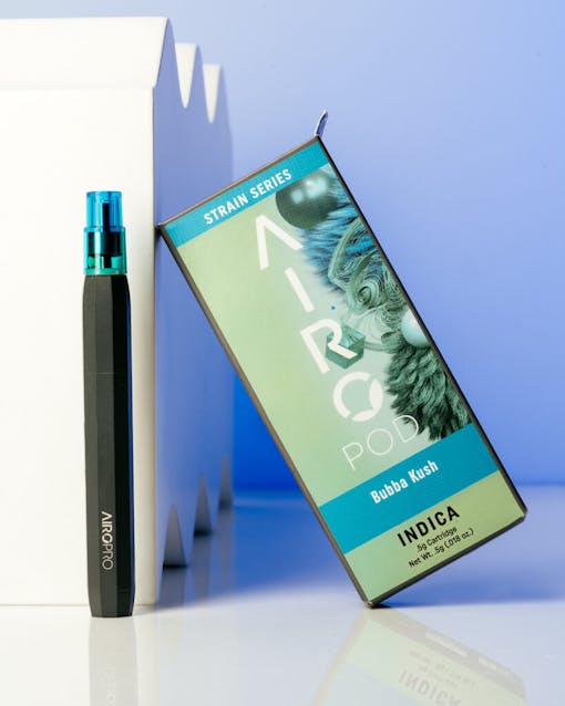AiroPod Strain Series product staged next to its packaging with white sculptural objects against a blue background.