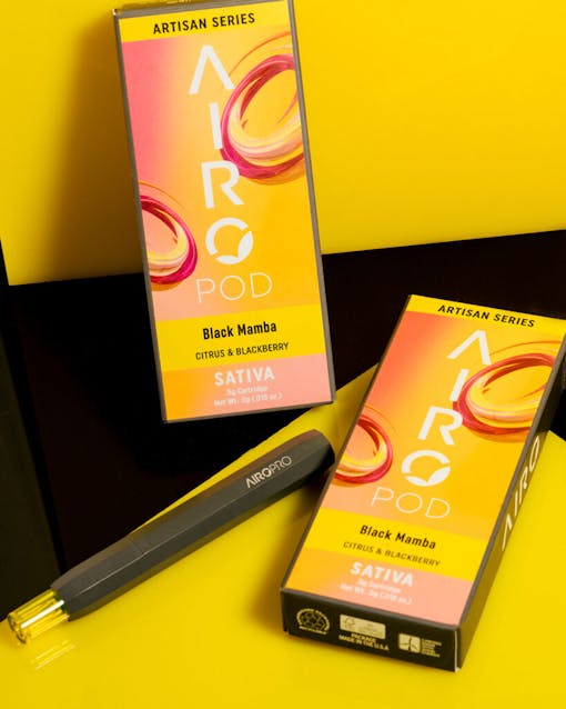 AiroPod Artisan Series product laying next to its packaging against a black and yellow background coordinating with the peach and yellow of the packaging.