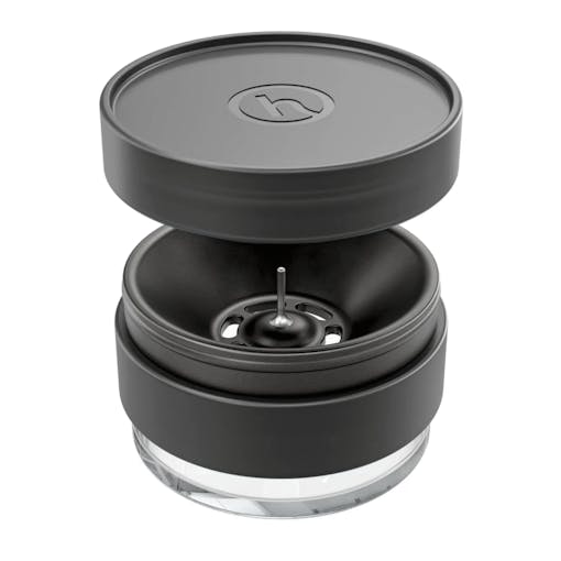 The Ashtray+ from Honest sits against a white background with its lid floating above the main section of the ashtray. The ashtray, one of our picks for the best back-to-school weed products of 2025, has a debowling pin in the middle of its design.